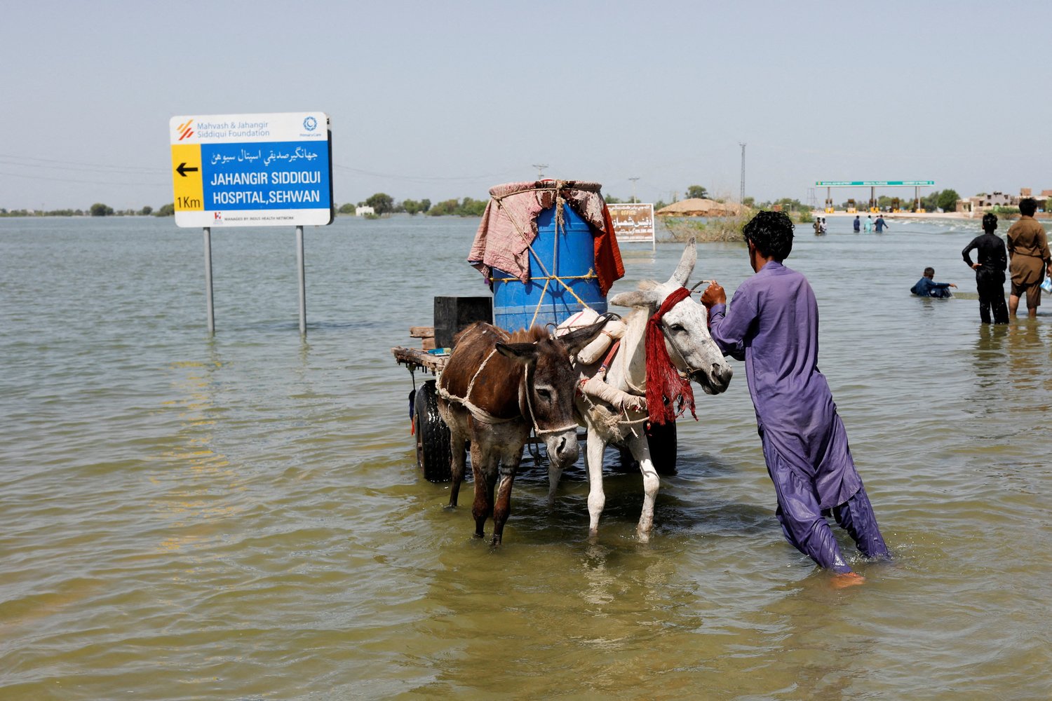 A flood victim pushes his donkey cart on a flooded highway following rains and floods in Sehwan, Pakistan Sept. 16 during a monsoon season impacted by climate change.