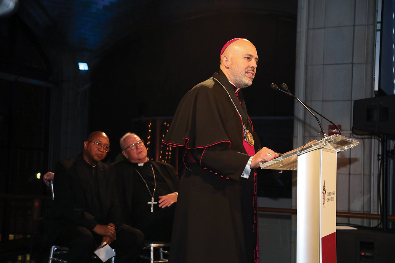 Auxiliary Bishop Joseph A. Espaillat, left, gives his award  acceptance speech at the Nov. 7 Pierre Toussaint Scholarship Fund Awards Dinner in Manhattan. Seated behind him are Brother Tyrone Davis, C.F.C., executive director of archdiocesan Office of Black Ministry, and Cardinal Dolan.